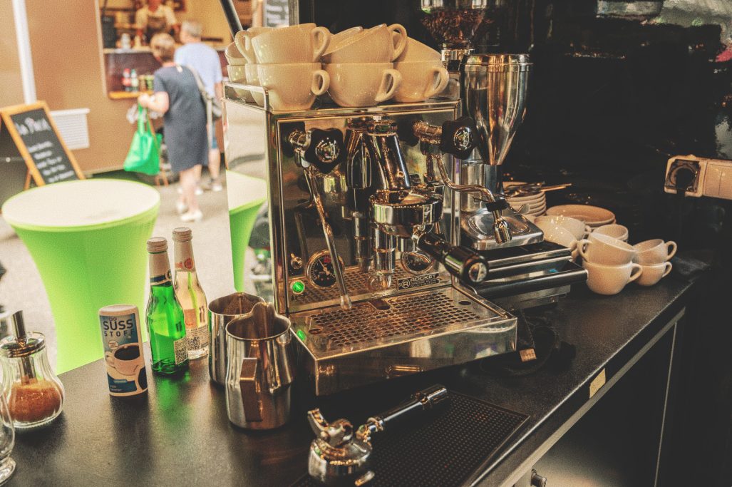 Eine Espressomaschine und Kaffezubehör auf einem Tisch im Freien.